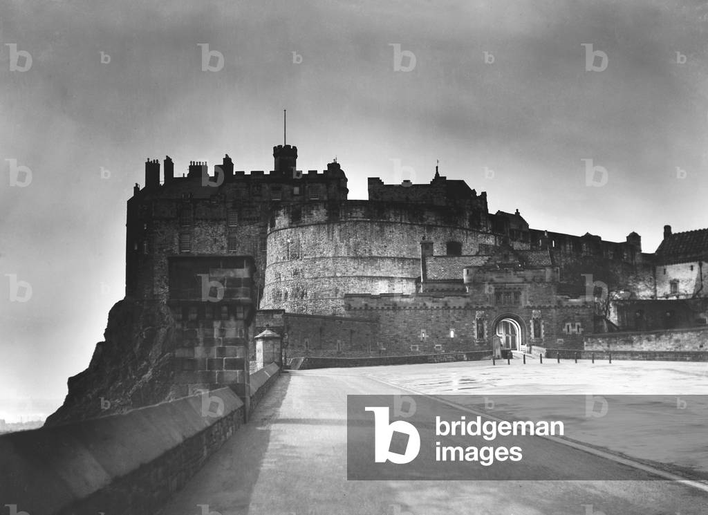 The light from Princes Street forms a halo around Edinburgh Castle as dusk falls on the Scottish Capital, c. 1935 (b/w photo)