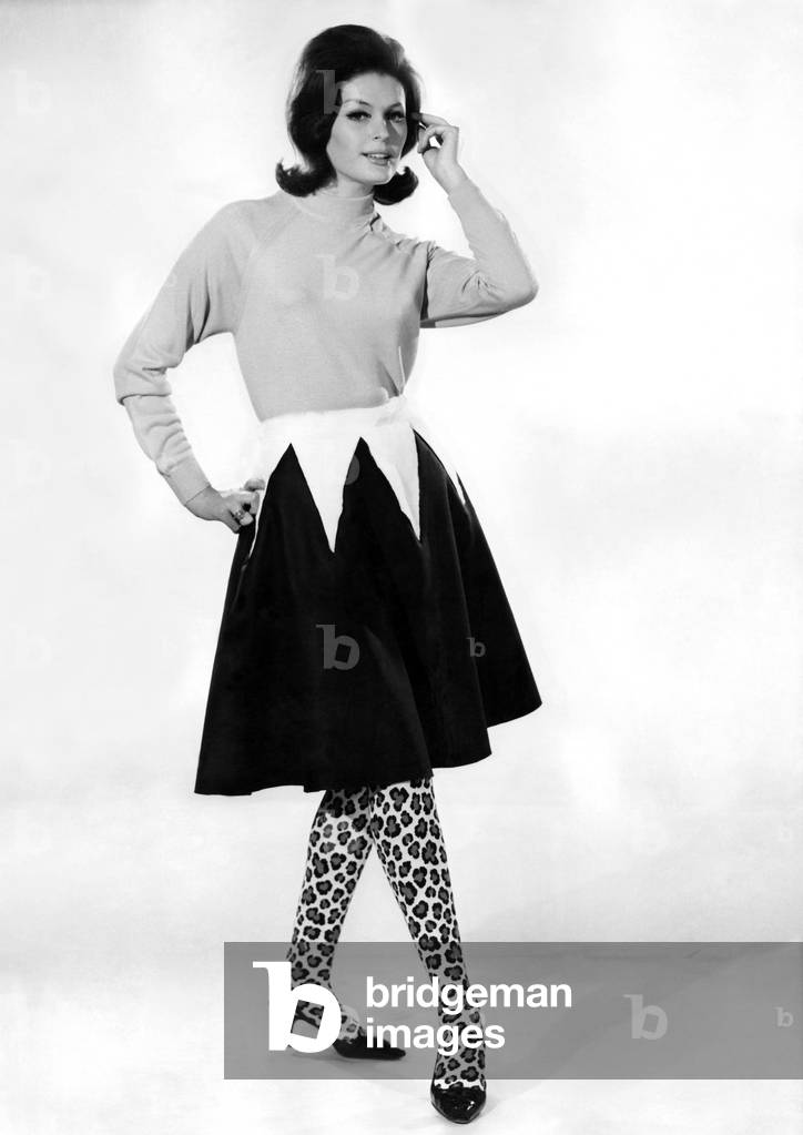 Clothing Misc. 1965: Gloria James modelling sweater, two tone skirt with animal print tights. January 1965