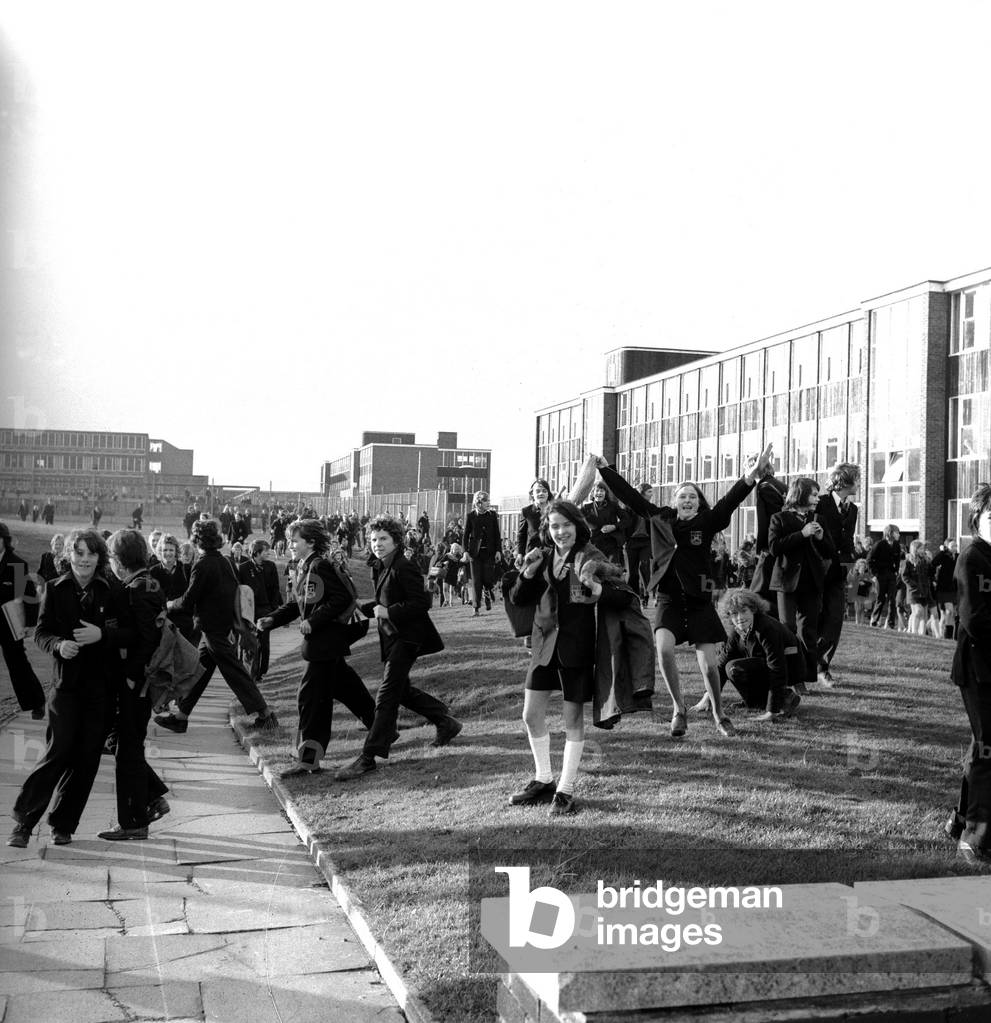 Pupils storm out of Kenton School, Newcastle, and run round the grounds chanting in protest at having to wear school uniforms, on November 11, 1974 (b/w photo)
