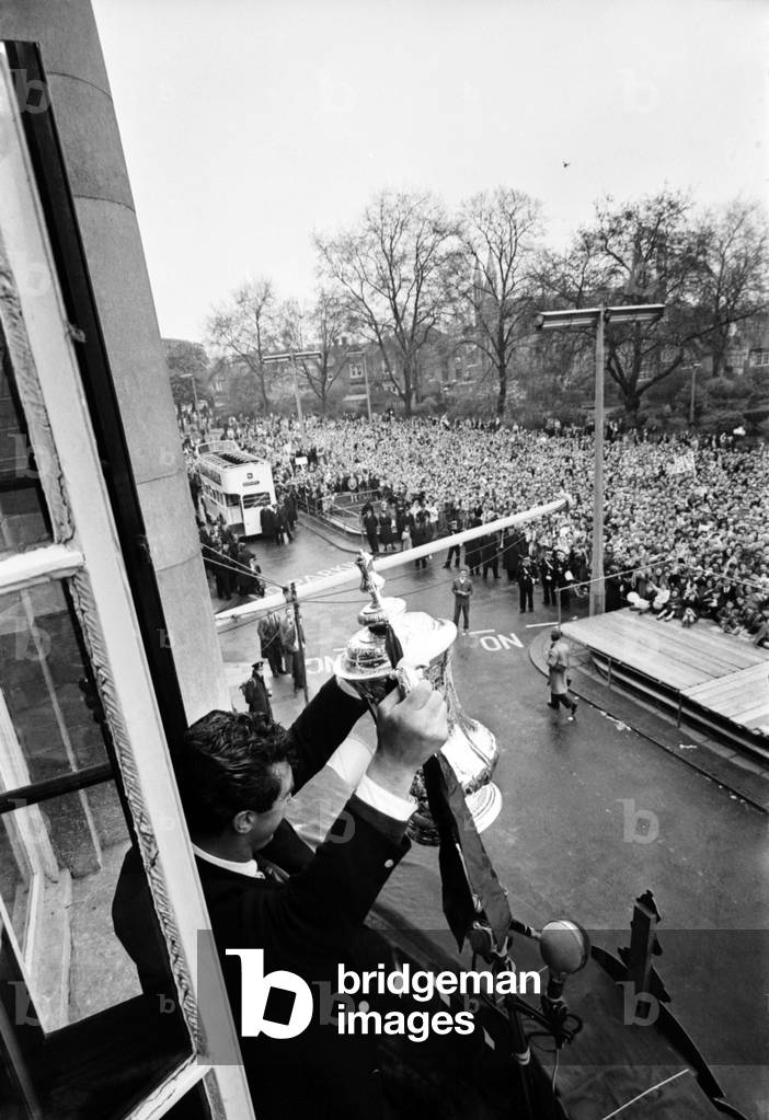 Tottenham Hotspur team hold the FA Cup trophy aloft at Tottenham Town Hall to a crowd of fans as they arrive home after defeating Burnley 3-1 in the FA Cup Final at Wembley. May 1962 Q3890-023 (photo)