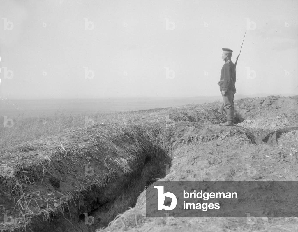 Russian sentry stands guard over trenches overlooking the village of Halicz and the Dniester River, August 1914 (b/w photo)