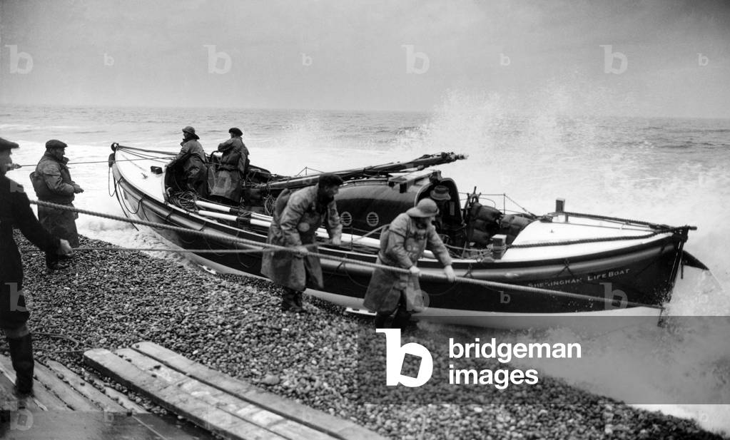 Lifeboatmen of Sheringham, Norfolk stand by during operational flights over the North Sea to rescue airmen who may have dropped into the sea on their way out to or returning from missions abroad. Here they are pictured getting the lifeboat in position for hauling ashore 12th January 1944 (b/w photo)