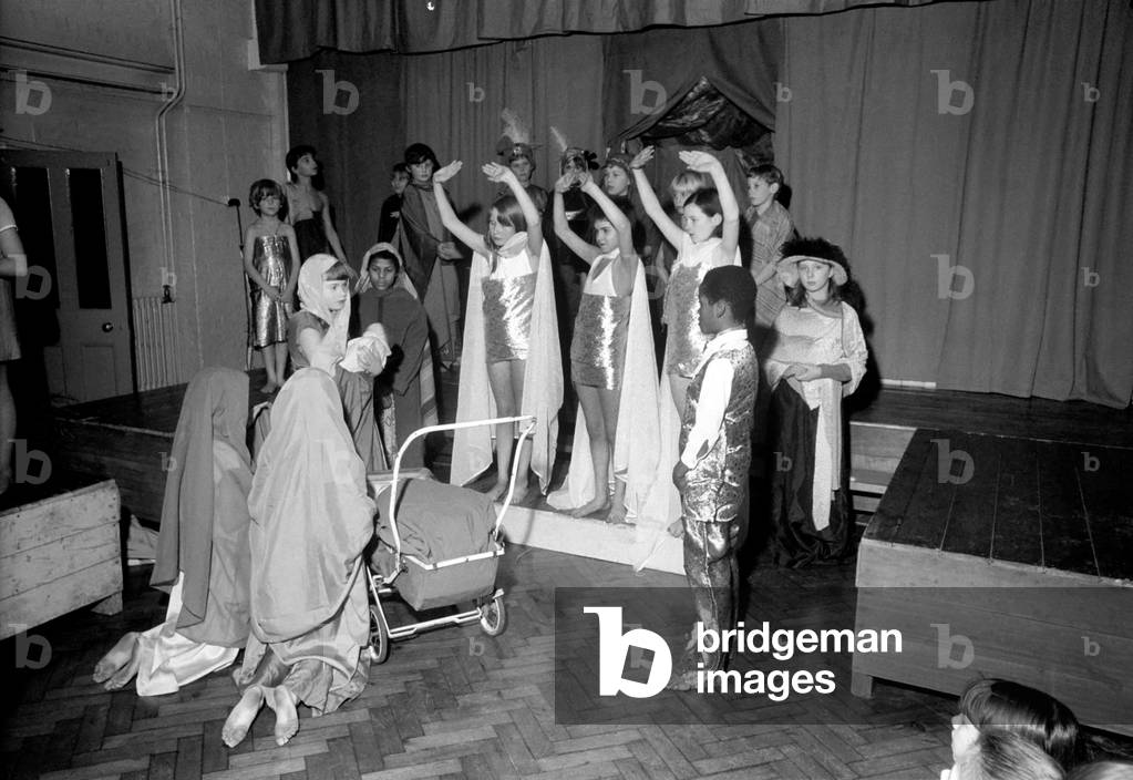 A Hippie street singer, and Mary pushing a pram, were part of a school's Christmas pageant put on by the children of St. James' Norland School, Penzanza Place, Notting Hill. Angels bless Mary and baby, Hippie singer and Joseph watching. December 1969