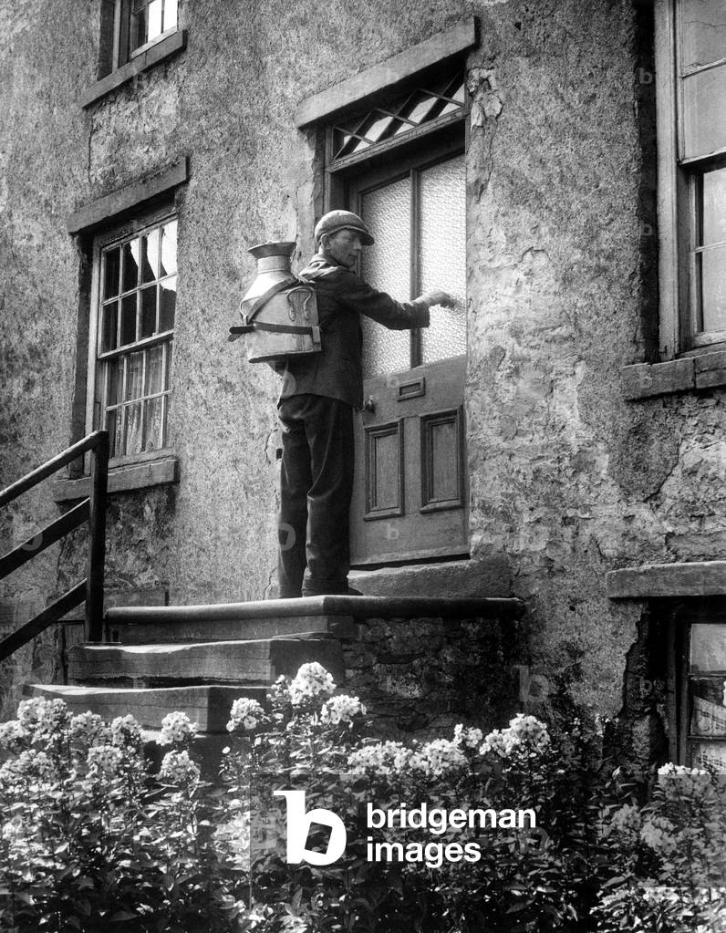 Village milkman George Wake doing his daily rounds in the Yorkshire Dales with his four and a half gallon milk can strapped to his back. 8th August 1944 (b/w photo)