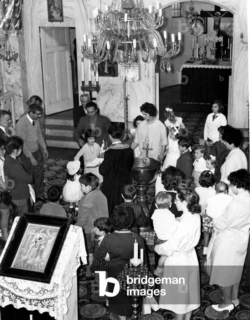 The scene inside the Greek Orthodox Church furing the ceremony to christen and confirm five young children. Incense burns as friends and relatives gather round the front of the little church - August 1962