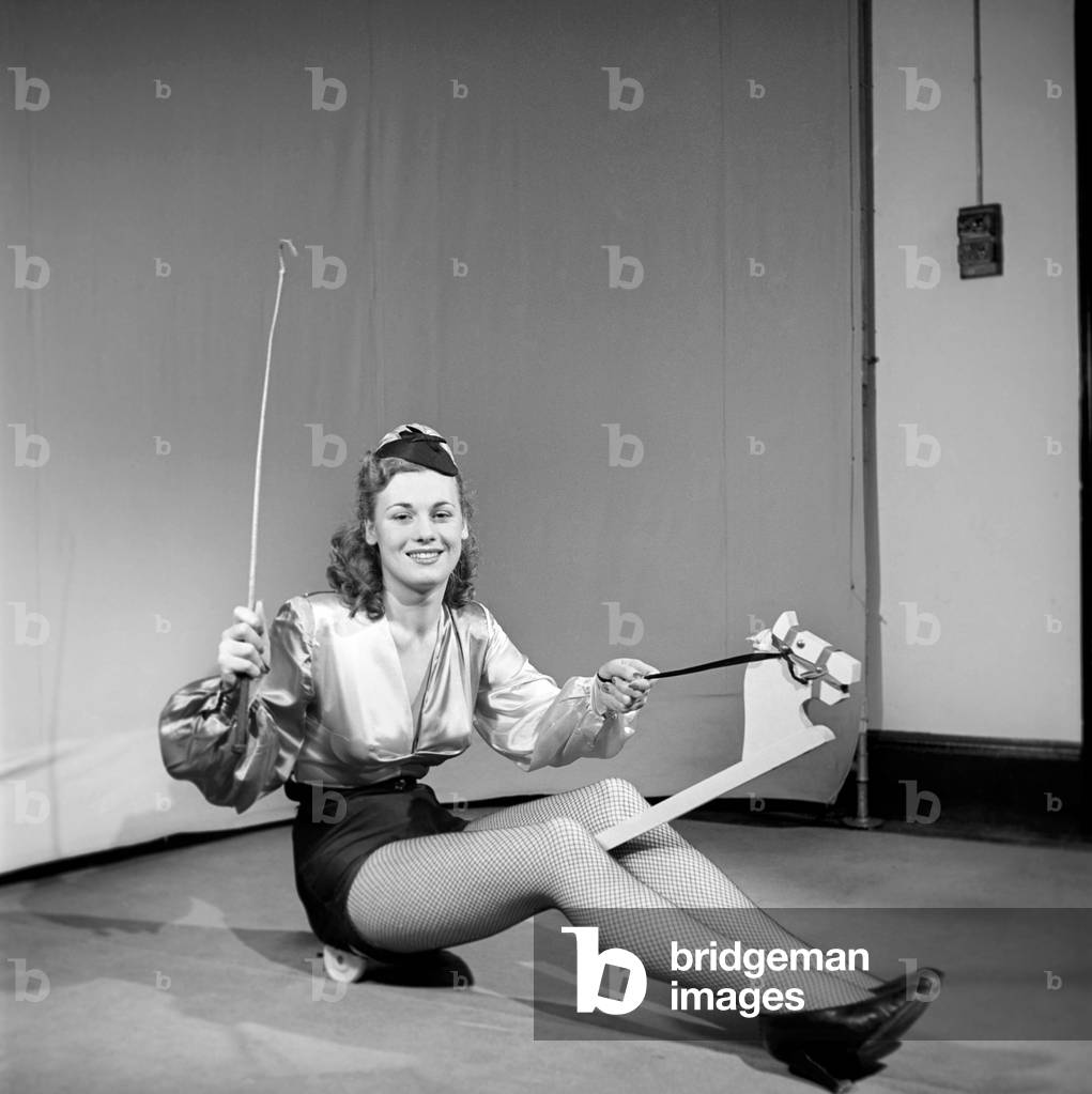 Woman wearing fancy dress jockey outfit, 1959 (b/w photo)
