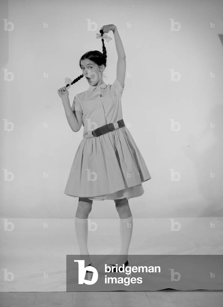 Model Jennifer Goddard. Brown-haired girl in chequered dress with pig tails, 03/09/1956 (b/w photo)