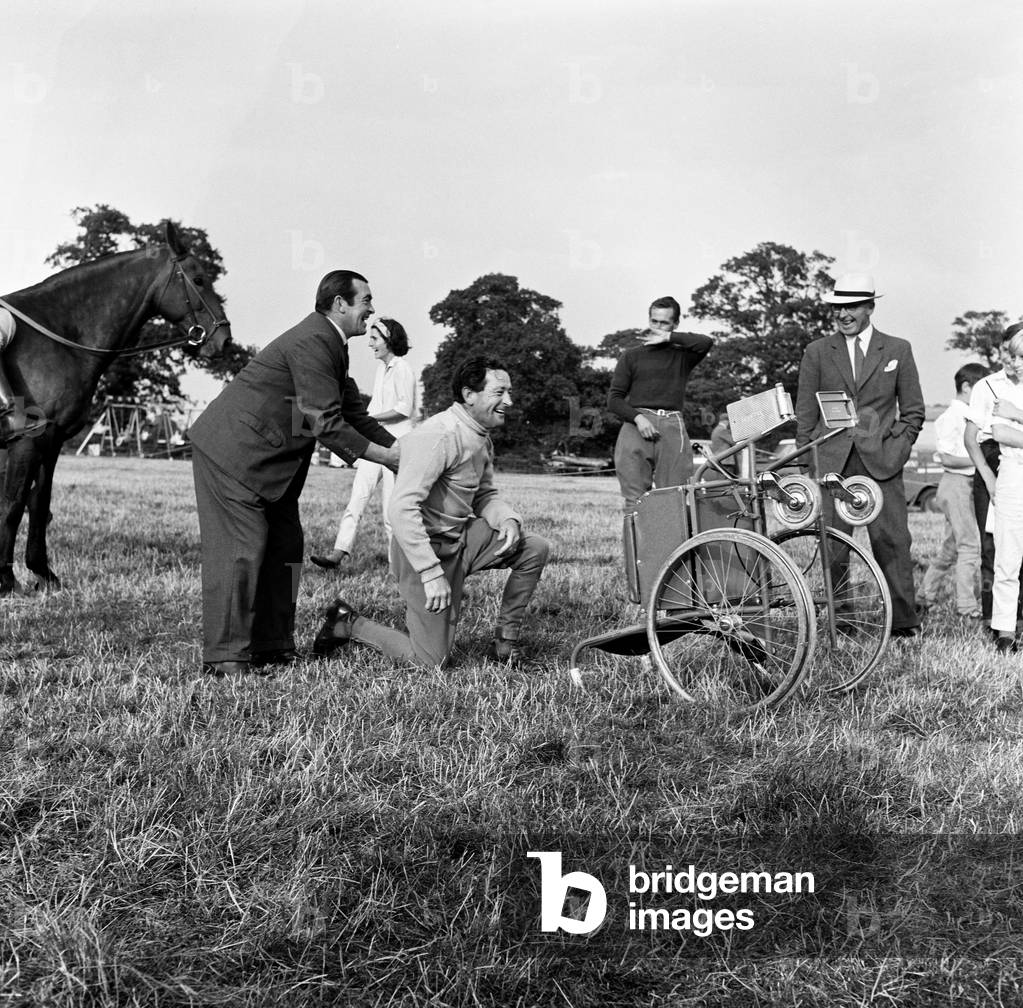 Finmere Jumping Show and Gymkhana near Buckingham in aid of Stoke Mandeville Games. Injured steeplechase jockey Tim Brookshaw shows Fred Winter a trick with his wheelchair and Fred comes to grief. 11th August 1964 (b/w photo)