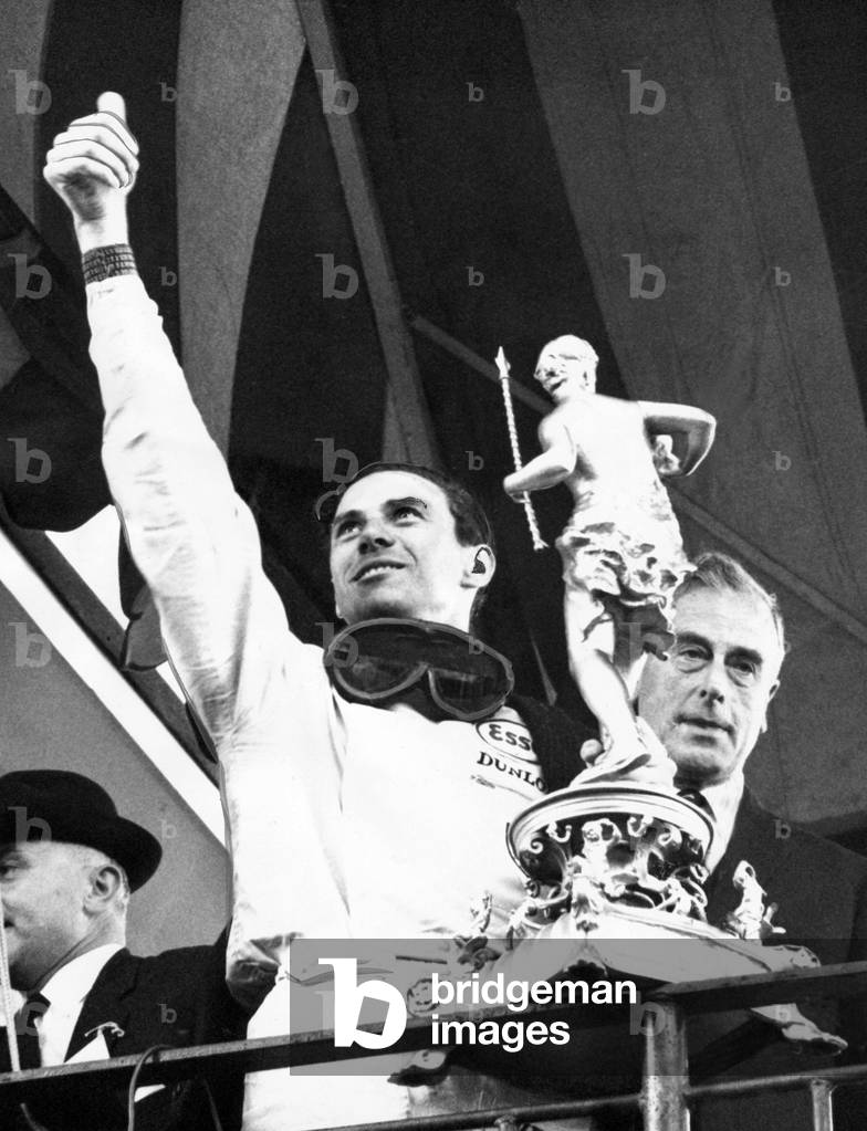 Jim Clark waves to the crowd as he holds the trophy presented to him by Earl Mountbatten, at Brands Hatch
