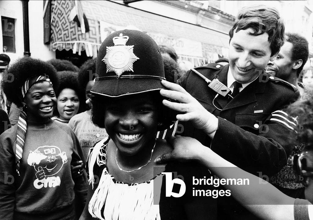 Woman wearing policeman's helmet. August 1978
