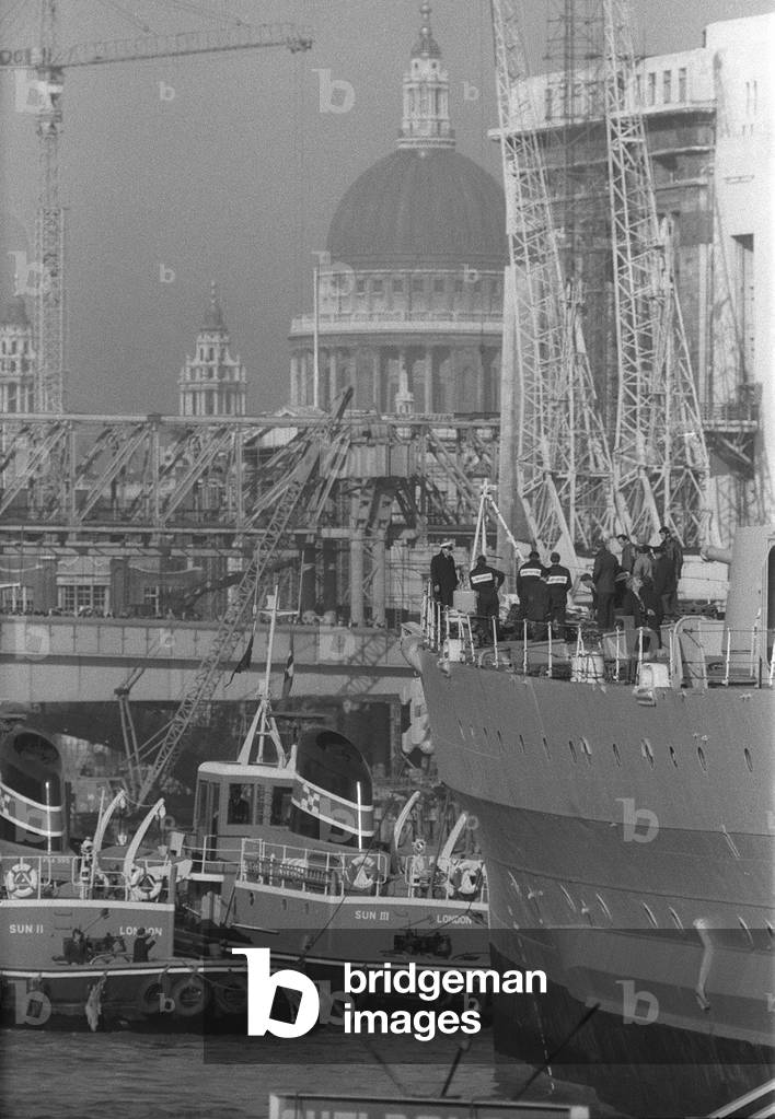 HMS Belfast sailing up the Thames passing St Pauls Cathedral to her mooring in the Pool of London where she will be opened to the public as a museum, 1971 (b/w photo)