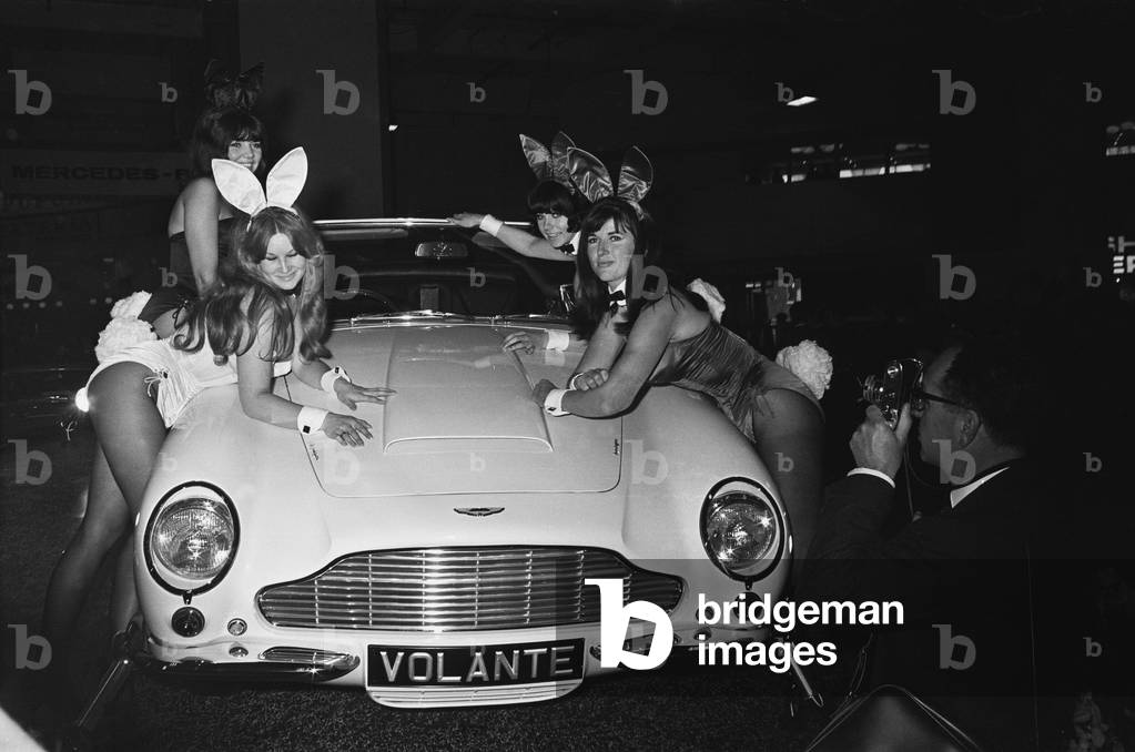Bunny Girls drapped over an Aston Martin Volante car at the British International Motor Show in London 19th October 1965.