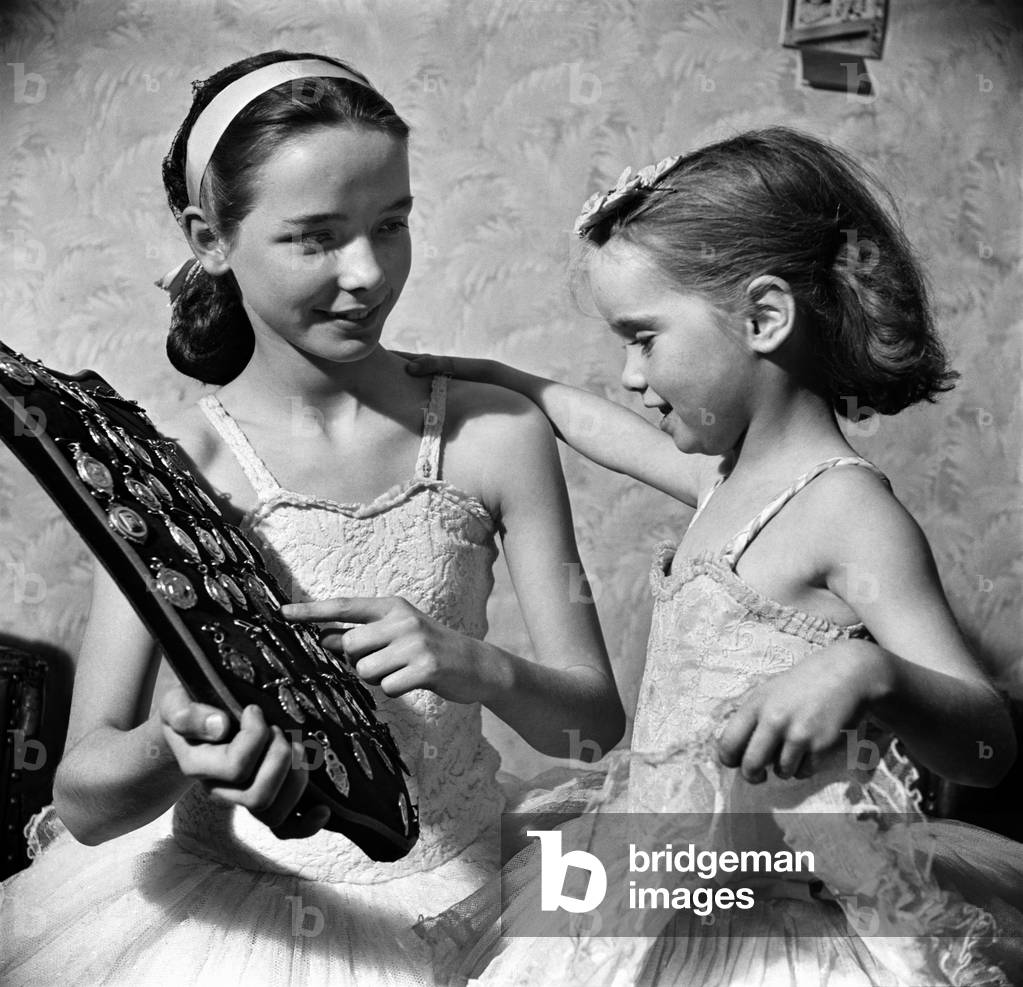 Anne Schofield, winner of 100 diplomas and 53 medals and cups shows Carol some of her medals during their Friday night practice. March 1952 C1343
