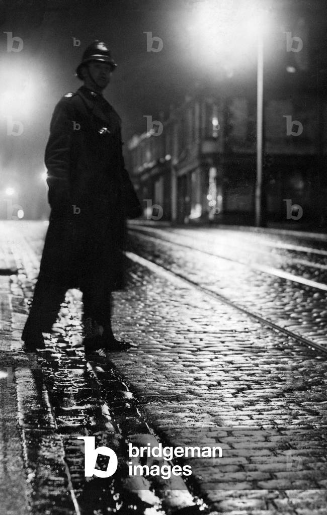 A lone police officer on beat during the night shift, c.1950