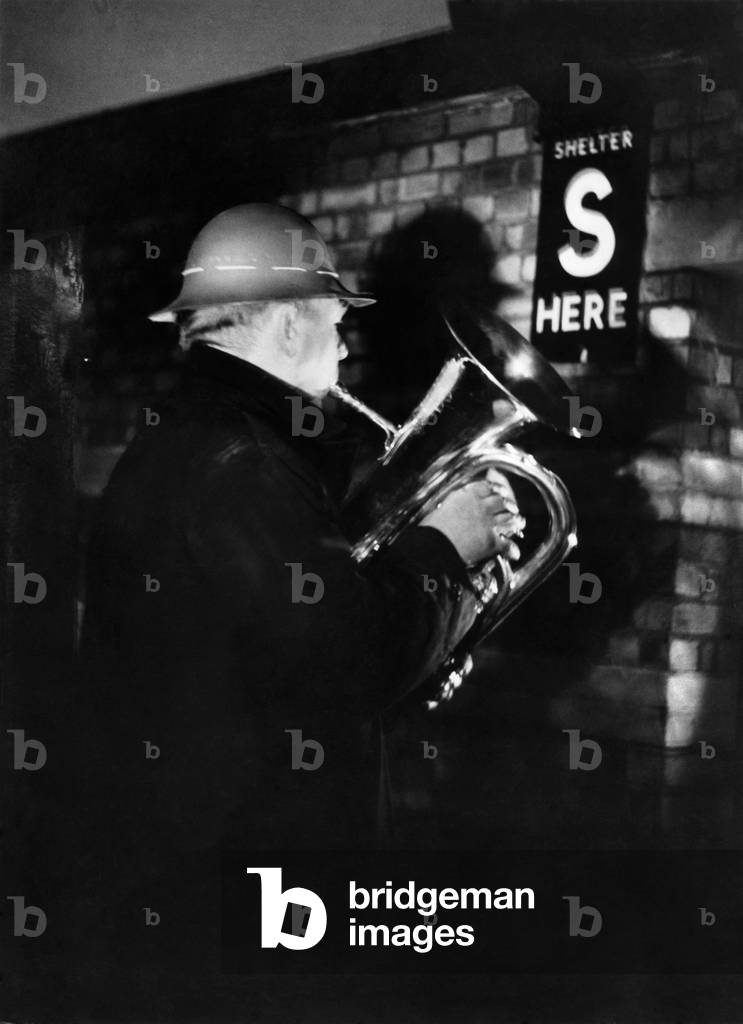 W.G. Dodge of the Wood Green Silver Prize Band plays Christmas Carols by moon light in shelter on Christmas Eve 24th December 1942 (b/w photo)