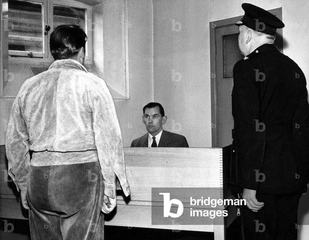 A prisoner is accompanied by a prison officer appears before the assistant governor Mr Hills to air his grievances at Barlinnie Prison in Glasgow Scotland June 1963 (b/w photo)