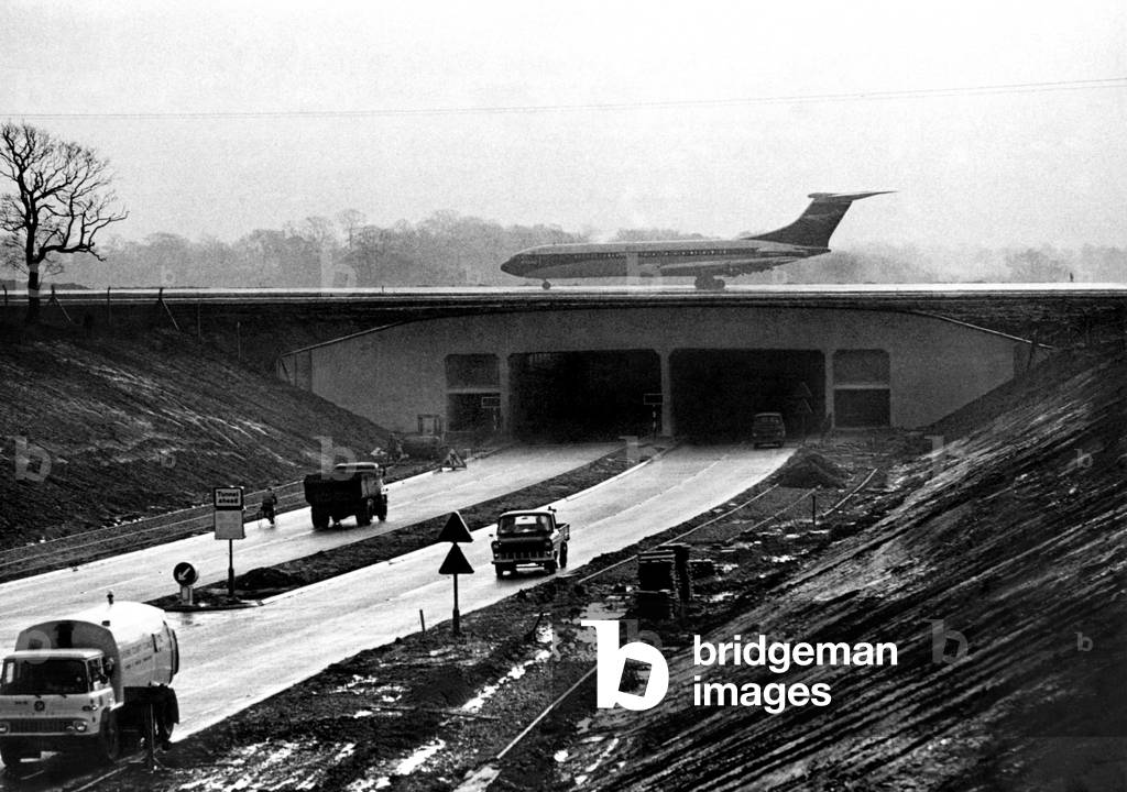 An airliner on Manchester Airport's new main runway extension which bridges the Altrincham-Wilmslow Road, Cheshire, January 1969 (b/w photo)