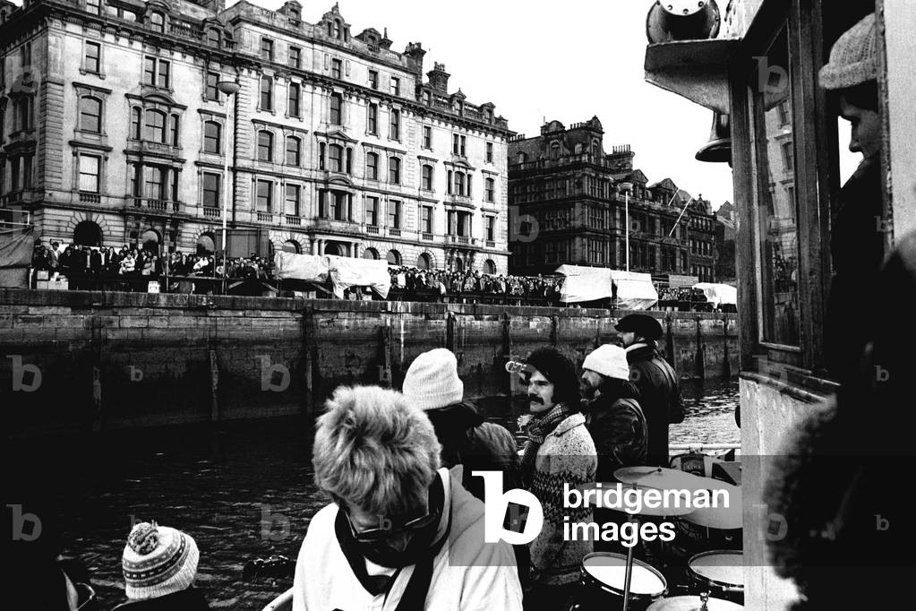 Lindisfarne sailed down the Tyne on a musical journey. The group were filming on board a Tyne ferry for a half-hour television show called 'All Right Now'. 4th March, 1979 (b/w photo)