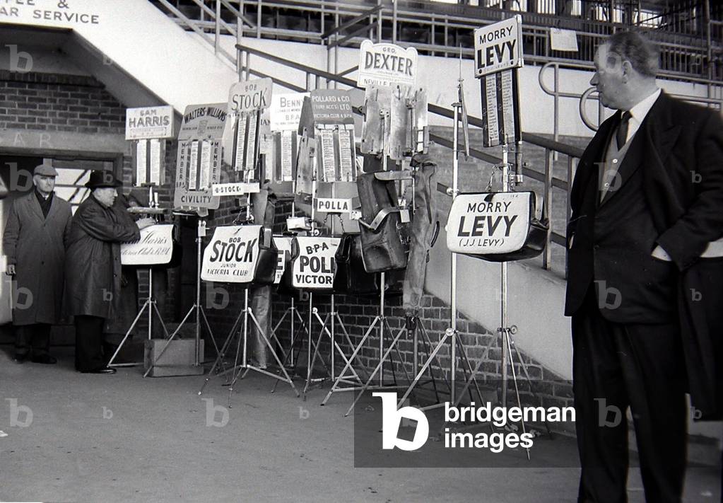 Bookmakers beside the main stand after bets were placed for the race, March 1963 (b/w photo)
