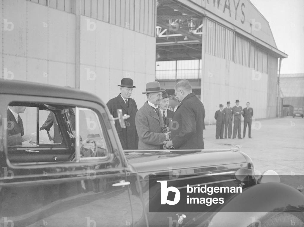 British Prime Minister Neville Chamberlain shakes hands with a German embassy official on his arrival at Heston airport following one of his meetings with German Chancellor Adolf Hitler in his Berchtesgaden mountain retreat, 16th September 1938 (b/w photo)