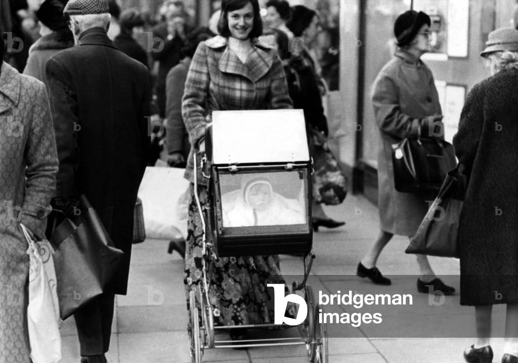 As prams go, it is very rare indeed. For it has windows. Little Nicole Fresco can thus see where she is going. and that, reports her mother Rosalyn, makes Nicole just about the happiest baby in their crowded High Street on 25th January 1973 (b/w photo)