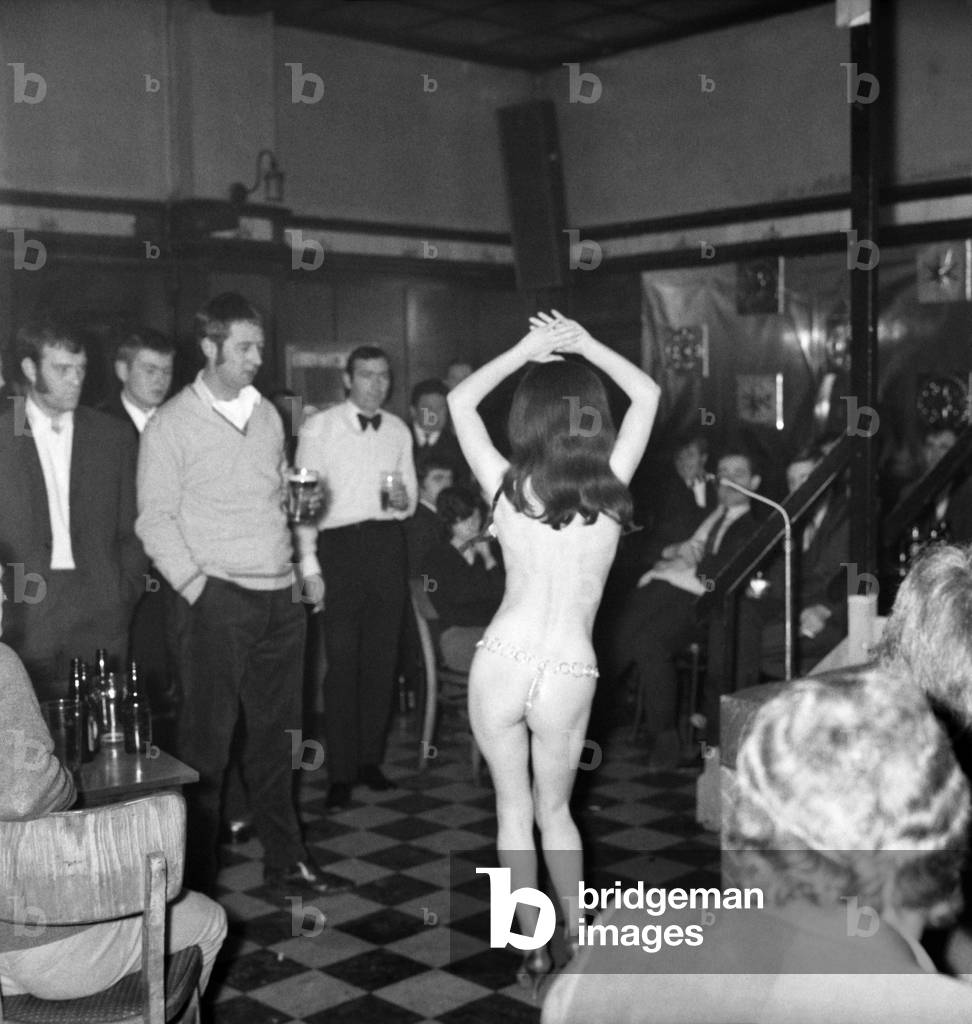 There is quite a lively atmosphere at the Montagu Arms Public House in Kender Street New Cross. A band is playing, compress sing and tell jokes and syas from time to time wait for it. And then eventually it appears and it is Stripper Jackie. Jackie appears dressed up as Charlie Chaplin and finished up more or less stripped the bear is excellent. November 1969