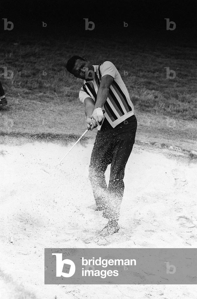 Boxer Sugar Ray Robinson relaxing with a game of golf trying to get the ball out of the sand bunker Although undoubtedly one of the greatest ever to step into the boxing ring, Sugar Ray Robinson was never quite at home on the golf course, 06/09/1962 (b/w photo)