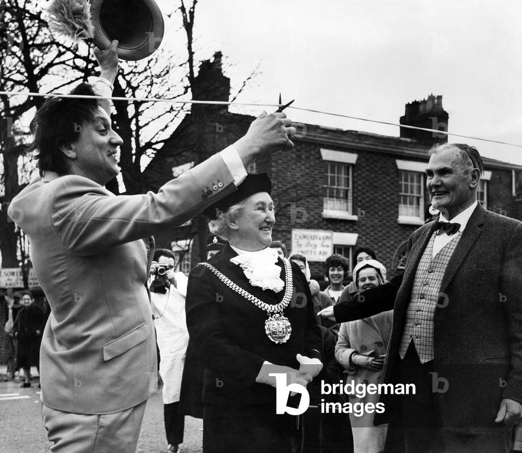 Ken Dodd cutting the tape to open the Knotty Ash community centre, with him is Dame Ethel Wormald, Mayor of Liverpool. 24th February 1968 (b/w photo)