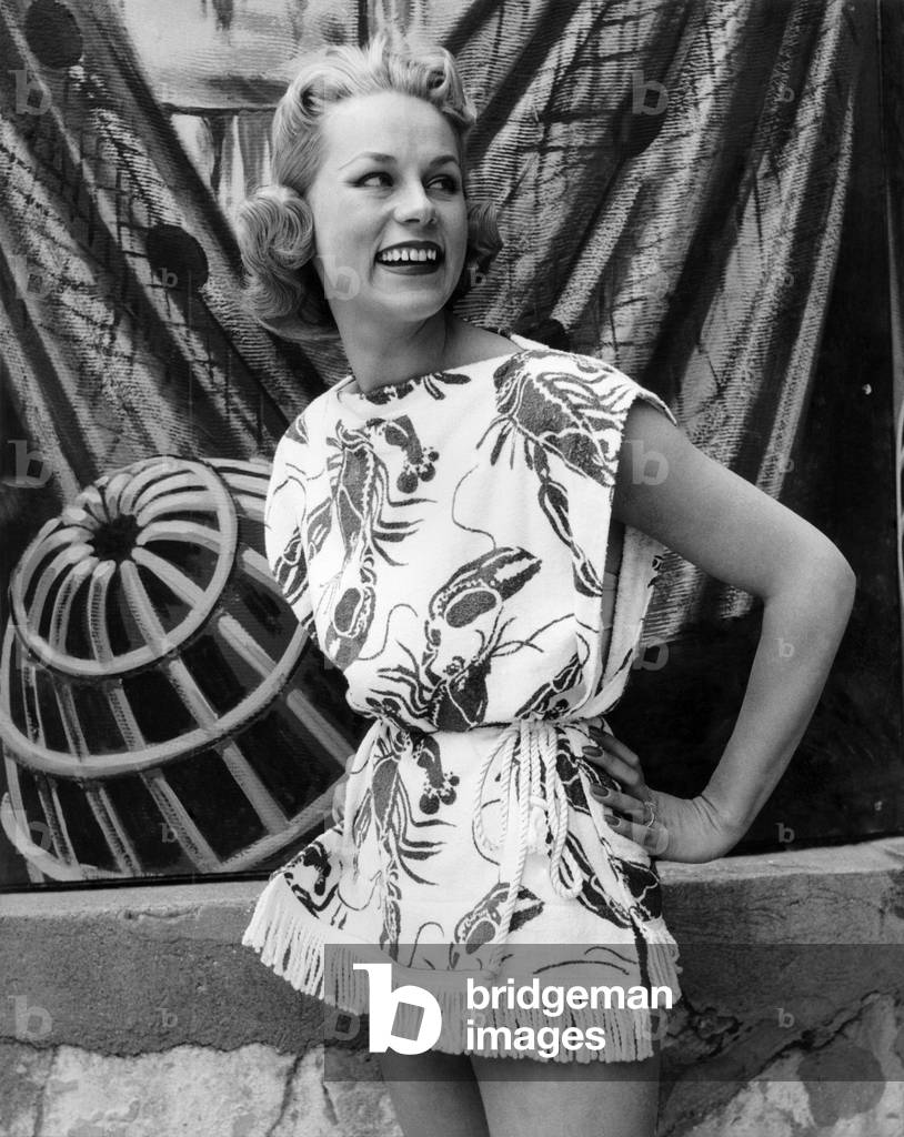 Woman wearing a patterned sleeveless short skirted outfit for a day out to the beach.
July 1955