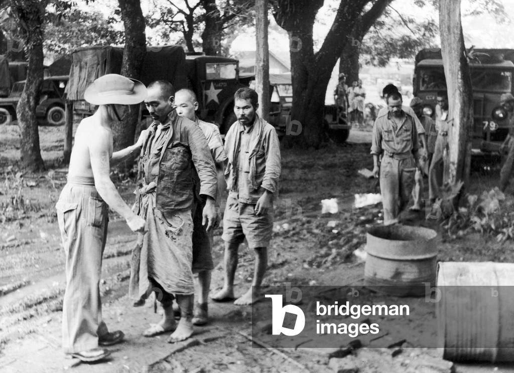 Japanese Prisoners of war are searched by Lance Corporal Smith after they were taken prisoner by British forces during the last stages of the Japanese breakthrough along the Toungoo-Pegu road in their attempt to reach Siam during the Second World War, 10th August 1945 (b/w photo)