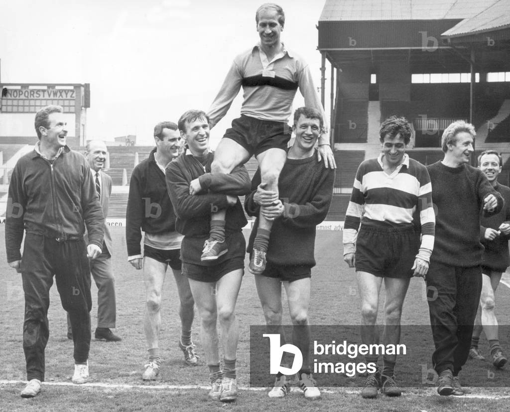 Manchester United footballer Bobby Charlton is carried around Old Trafford football ground on the shoulders of his teammates Pat Crerand and David Herd after being named 