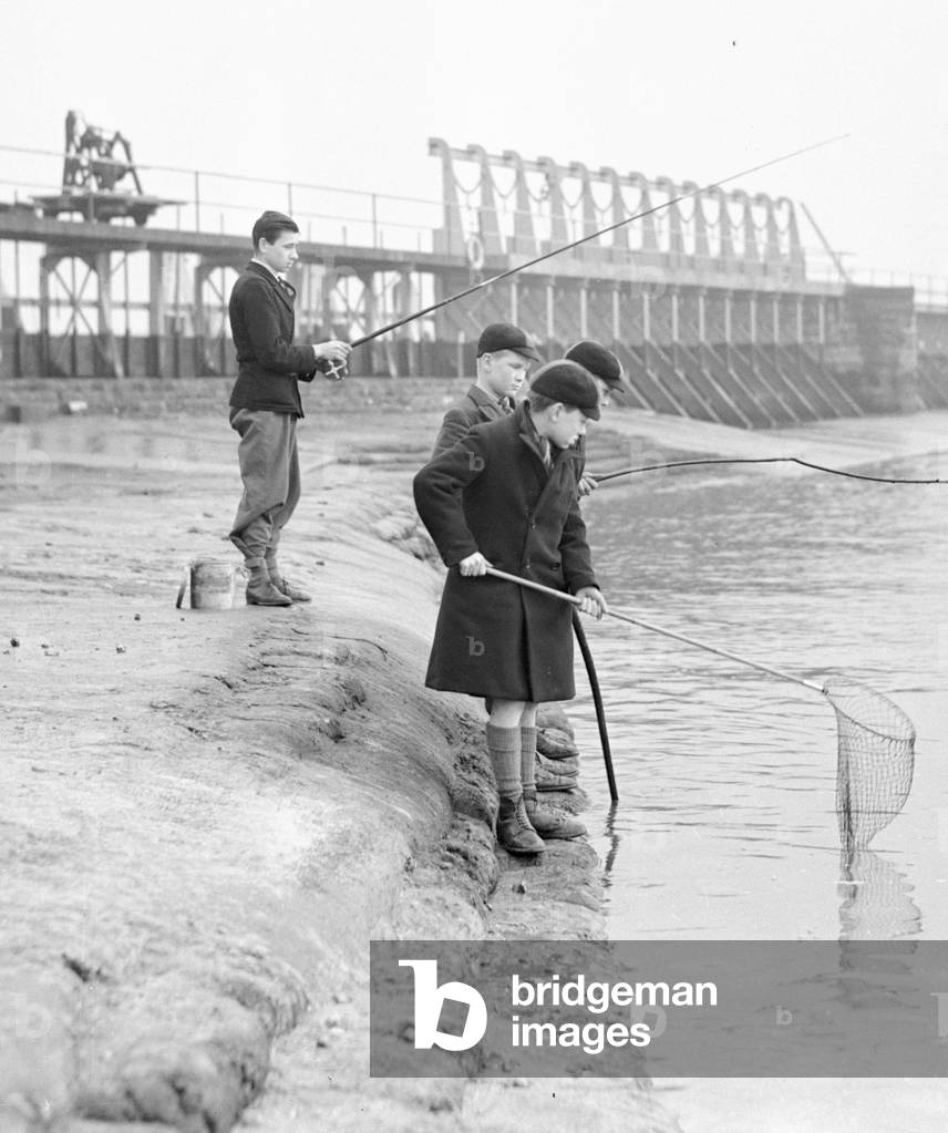 Schoolboys fishing at Teddington Weir during the winter drought of 1933