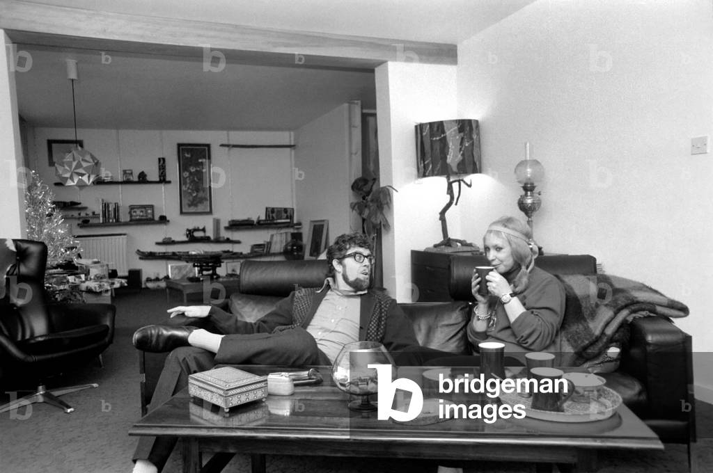 Singer Rolf Harris who lives in Sydenham, Kent, has bought the house adjoining his own modern terrace. He decided he would like to enlarge the three bedroomed house and knocked down the brick wall between the houses, himself. Rolf and his sculptress wife Alwen live their with their five year old daughter Bindi. Rolf with his wife Alwen sitting in the new house. In background is the old house. December 1969