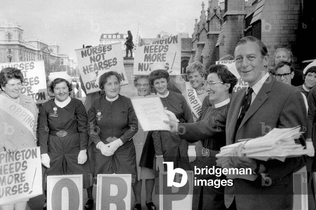 Uniformed nurses from Orpington Hospital went to the House of Commons today to hand over a petition to parliament to Mr. Eric Lubbock, MP for Orpington. Nine nurses carried from 30,000 petition signatures in large white boxes each painted with the letter from the word 'Orpington' and on the reverse side each box bore a red cross. The nurses were accompanied by several Citizen Members of the Orpington Nurses and Citizens Association. Although the petition refers specifically to Orpington Hospital, it is known that a shortage of nurses is affecting many hospitals in Britain. The nurses were not agitating for more pay and less working hours, but they were calling specifically for increased nursing establishment - in other words authority to recruit more nurses. 
Mr. Eric Lubbock, M.P. Orpington, pictured with the nurses holding their white boxes containing the signatures.
November 1969