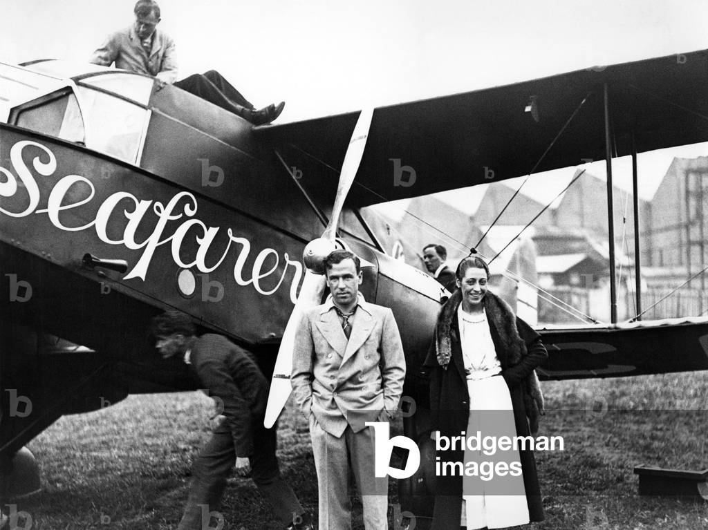Mr and Mrs. J Mollison, otherwise known as Amy Johnson, standing beside the De Havilland Dragon plane 