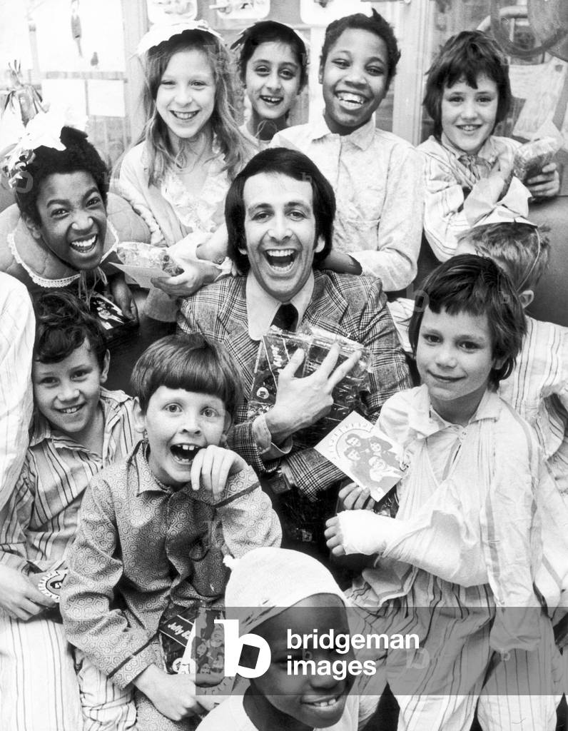 Don Maclean, actor and comedian, makes guest appearance and hands out gifts to children in hospital ward, 5th April 1974 (b/w photo)