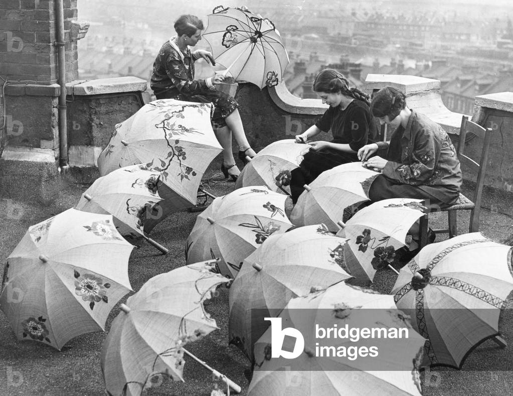 Parasol Novelties. The latest raffin summer parasol seen here being decorated by artist on the roof of the Emvigo Studios in Hampstead. 1st May 1927