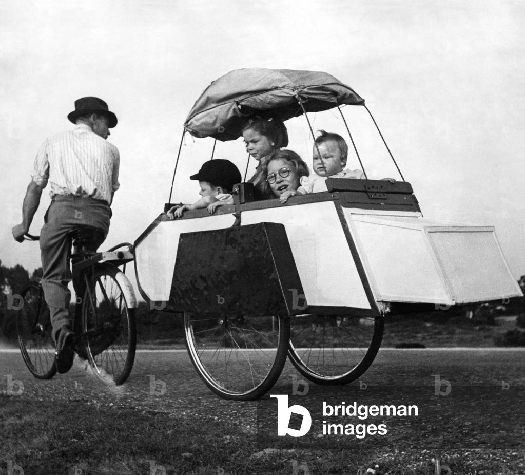 Transport: Cycles: Four of the family in the trailer. Baby Sonia age 10 months, Molly age 7 years (wearing glasses), Rose age 4 years end Bobby age 4 years. August 1949 (b/w photo)