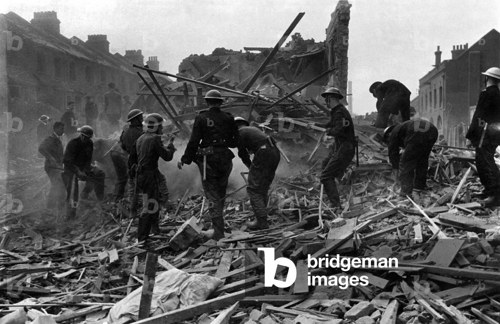 Flying bomb incident in Southern England showing demolished houses and sa treet surface shelter. Rescue efforts by NFS firmen and Civil Defence workers free casualties trapped at the scene soon after incident. August 1944