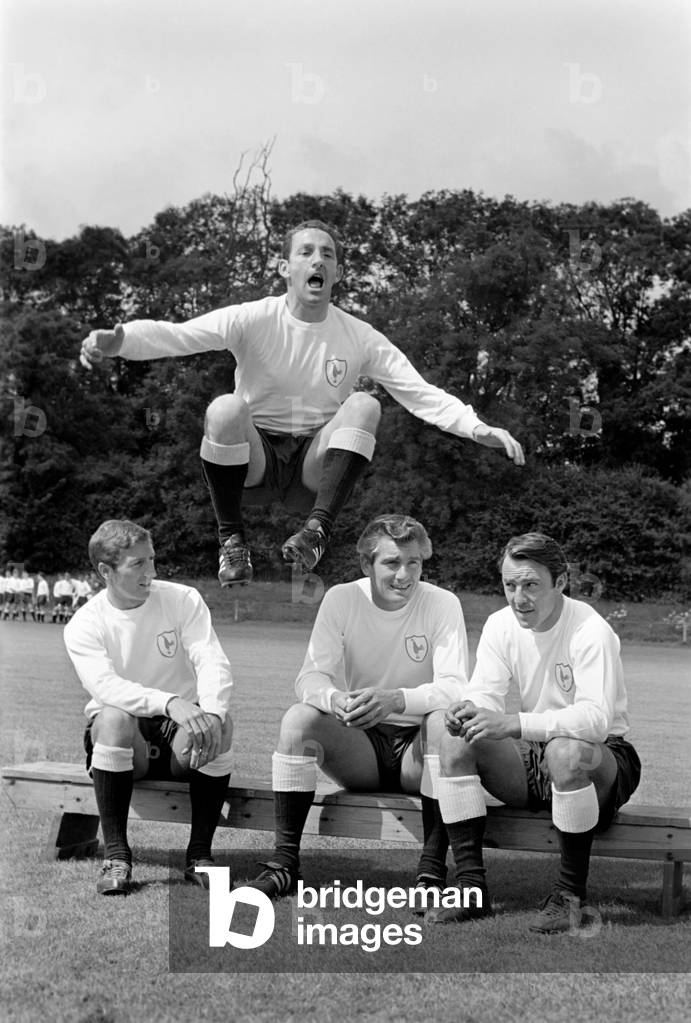 Members of the Tottenham Hotspur team training. Dave Mackay jumping high as teammates sit on the bench talkingJuly 1965 1965-1971-036 (photo)