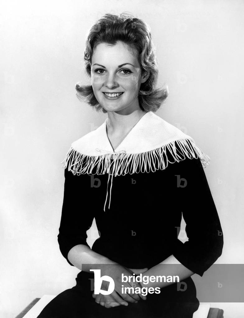 Woman wearing long dress with tassle ffefature around the collar, March 1960