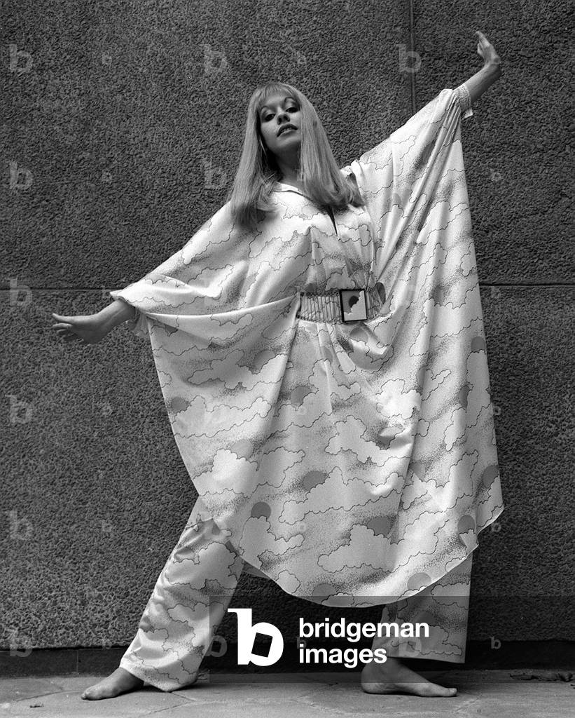 Corina Scott in Simon Massey element print trouser outfit with cape / batwing sleeves posing with her arms stretched out