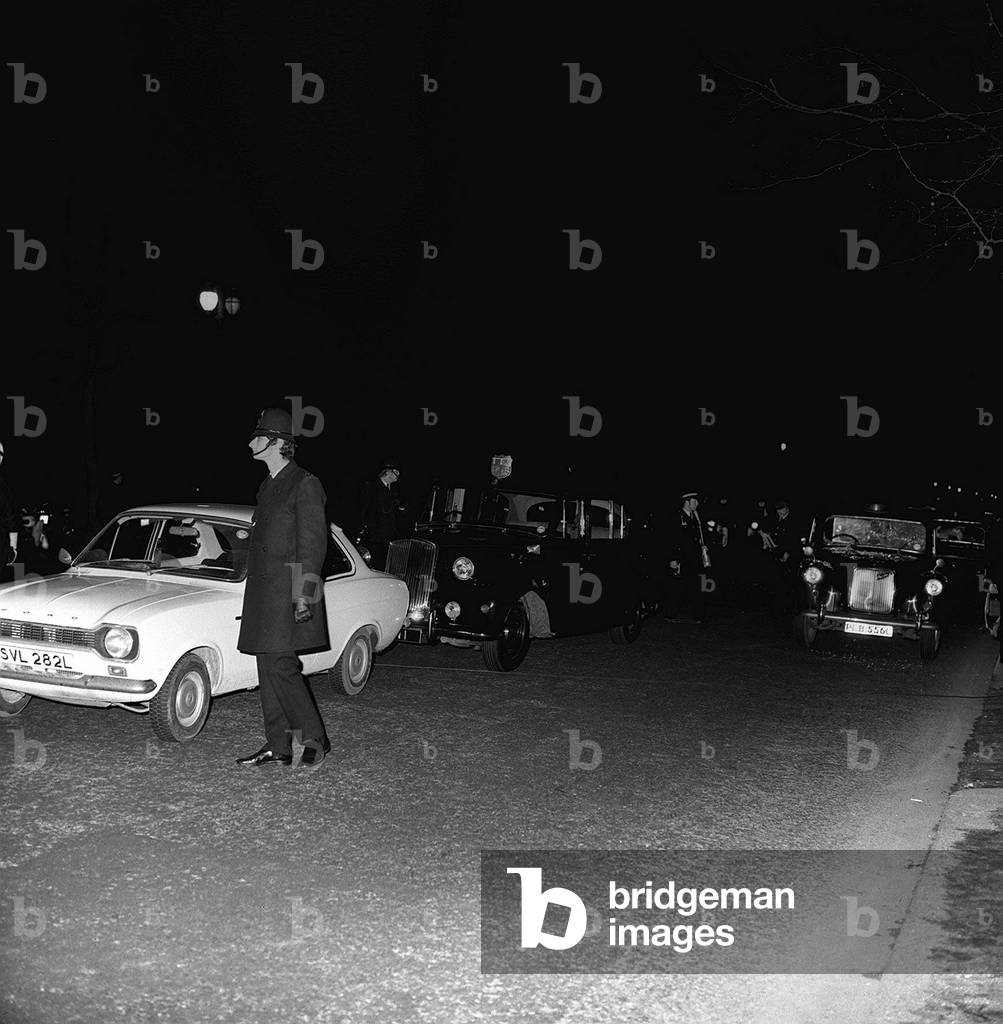 The Metropolitan Police surround the royal car and a Ford Escort after the attempted shooting of Princess Anne and Captain Mark Phillips in the Mall. The Royal car had been carrying Princess Anne and her husband Captain Mark Phillips when an armed gunman attempted to kidnap her as she drove up the Mall. T he kidnapper, Ian Ball, overtook the Princess in his Ford Escort before leaping from his car and firing six shots at the royal vehicle. One bullet somehow managed to pass between the Princess and her husband, yet neither of them were hurt. The kidnapper's plans were foiled when a royal bodyguard drew a pistol. Ball was arrested as he tried to make his escape. 20/3/74 R74/1771-9 Royals 73 Box 3 The Royal car had been carrying Princess Anne and her husband Capt. Mark Phillips when an armed gunman attempted to kidnap the Princess as she drove up the Mall. The kidnapper, a one Ian Ball overtook the Princess in his Ford Escort before leaping from his car and firing six shots at the royal vehicle. One bullet somehow managed to pass between the Princess and her husband, yet neither of them were hurt. The kidnapper's plans were foiled when a royal bodyguard drew a pistol. Ball was arrested as he tried to make his escape. 20th March 1974 (b/w photo)