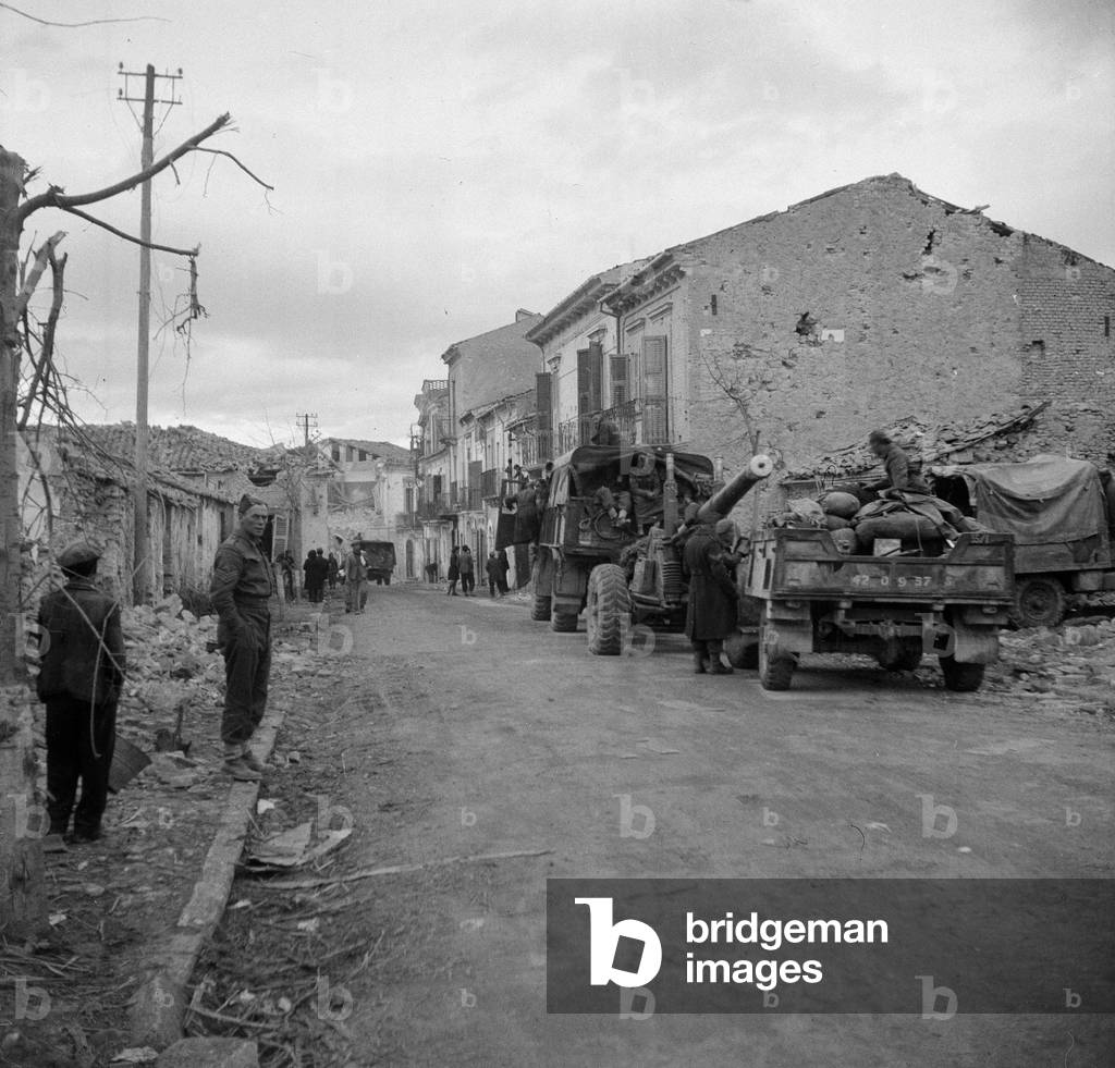 4.5 inch guns moving through Fossacesia to support the attack beyond St. Vito, Italy, 1943 (b/w photo)
