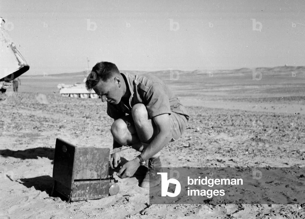 A soldier from 3rd County of London Yeomanry (Sharpshooters) using a stove in North Africa, 1942 circa (b/w photo)