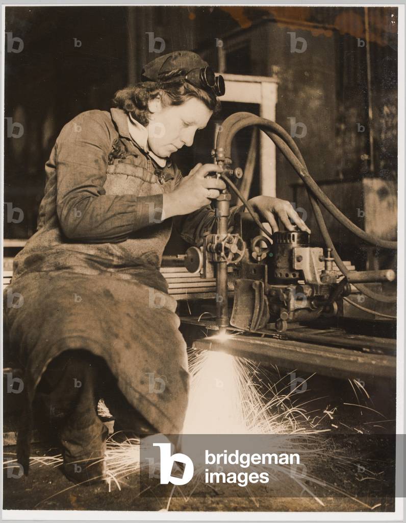 Miss Betty Crawford cutting steel plates with an oxygen and gas cutter, 1941 circa (b/w photo)