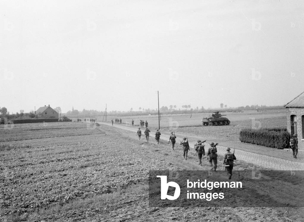 Infantry supporting A Squadron who were clearing isolated enemy infantry from the woods while enlarging the Gheel bridgehead, 1944 (b/w photo)