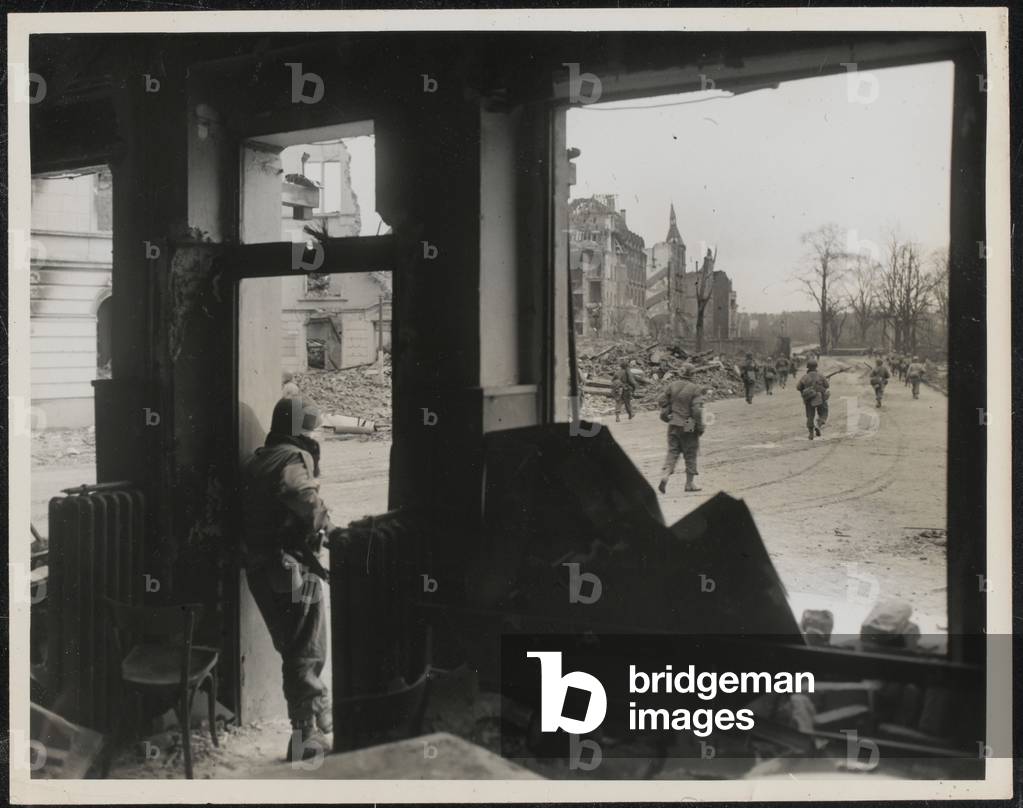 An American soldier watches a patrol moving towards the centre of Cologne, March 1945 (b/w photo)