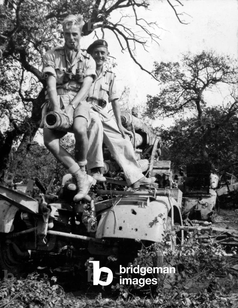 Two members of 3rd County of London Yeomanry sit astride a knocked out German 88mm gun in Italy, 1943 (b/w photo)