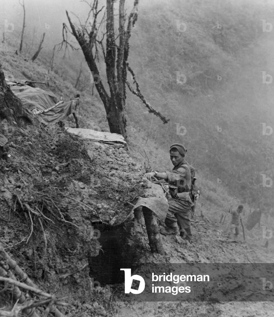 A Gurkha examines a Japanese bunker, Scraggy hill, 1944 (b/w photo)